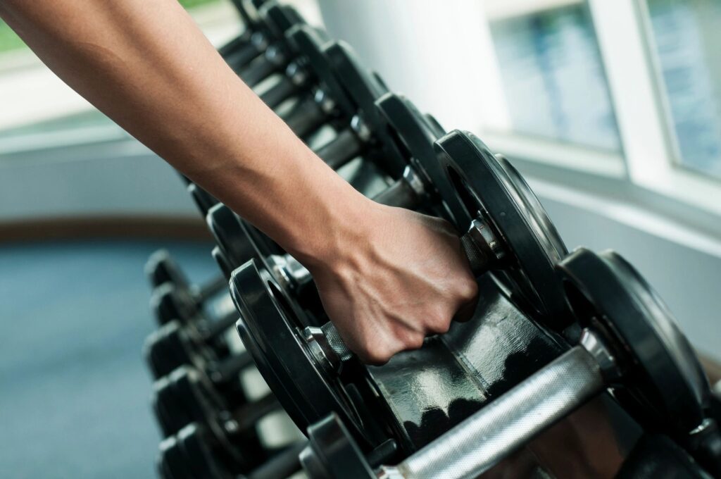 A person is holding onto some black dumbbells