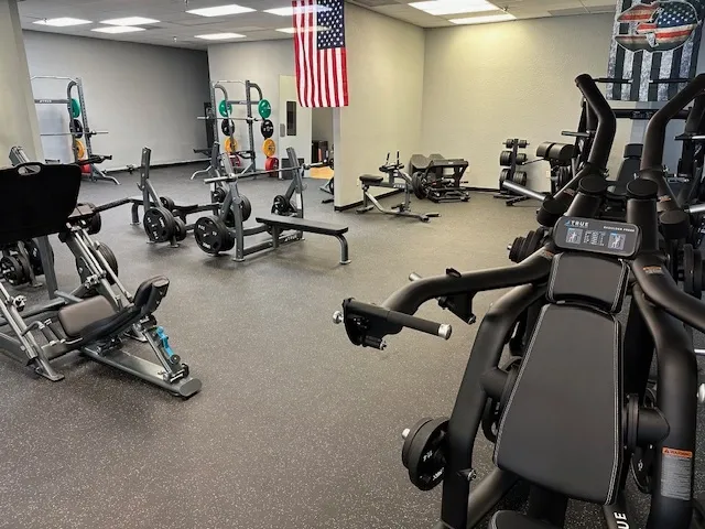 A gym with many different machines and american flag