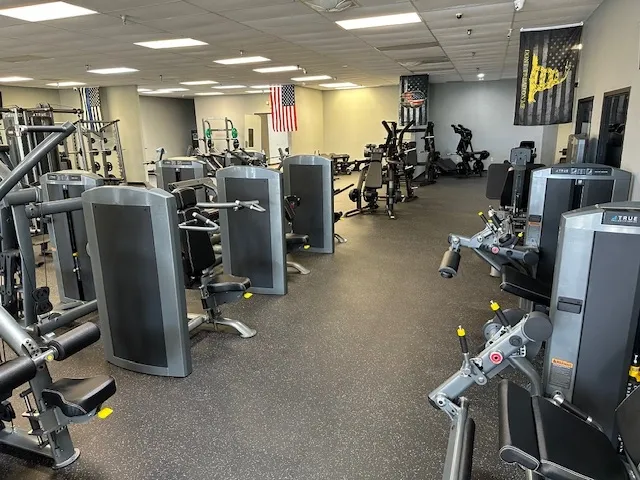 A gym with many machines and people in it
