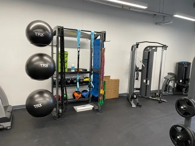 A gym with several different equipment on the floor.