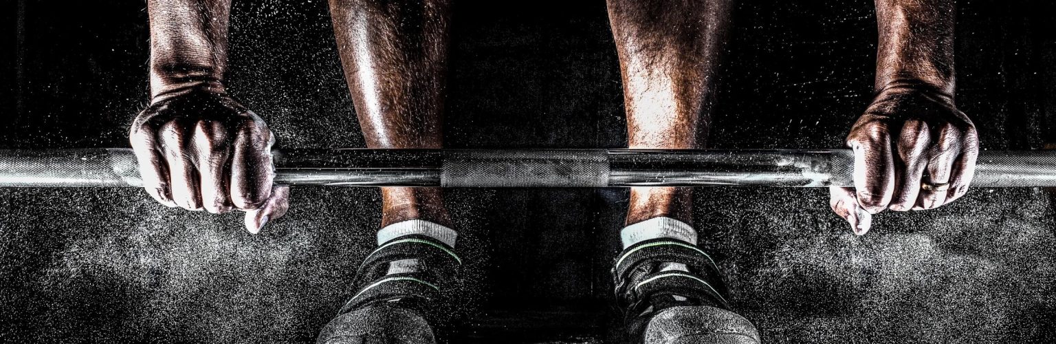 A man is lifting a barbell in the gym